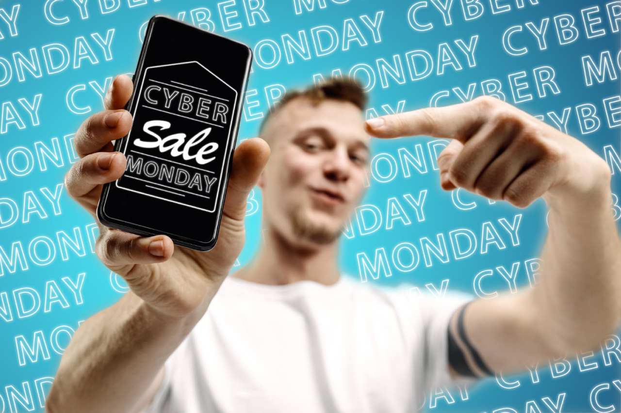 A person holds up a smartphone displaying a "Cyber Monday Sale" message, leveraging the psychology of online shopping, with a blue background featuring repeated "Cyber Monday" text. Cognitive biases influences buyers' decision making.