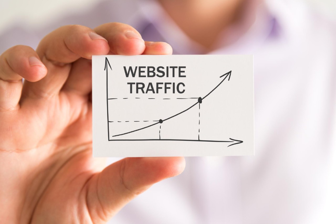 A person holds a card displaying a graph with upward trend lines and the words "Website Traffic" above the chart, highlighting how effective SEO strategies are essential for driving traffic and supporting business growth.