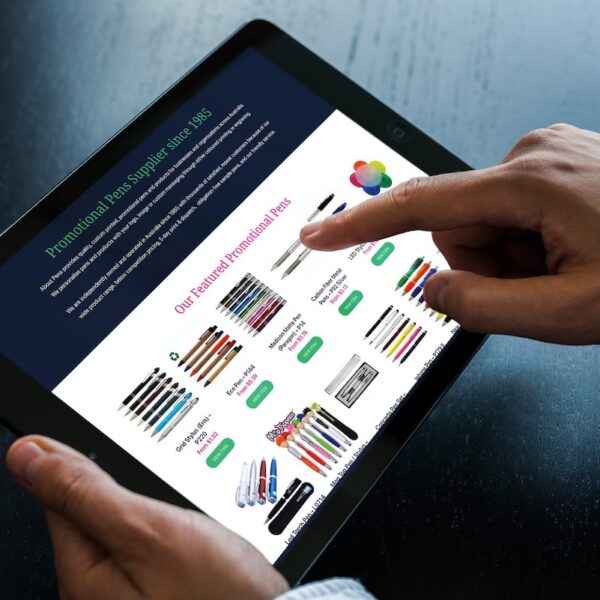 A person holding a tablet with a website on it, promoting promotional pens.