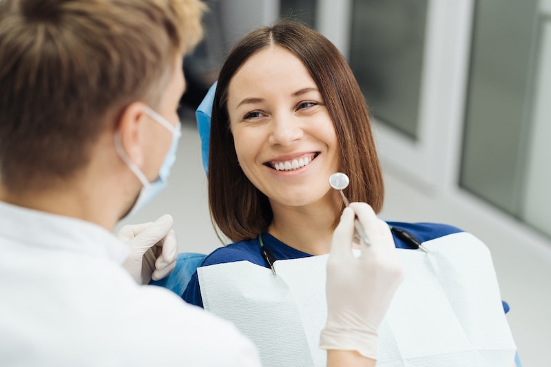 A woman smiles while visiting a dentist at home.