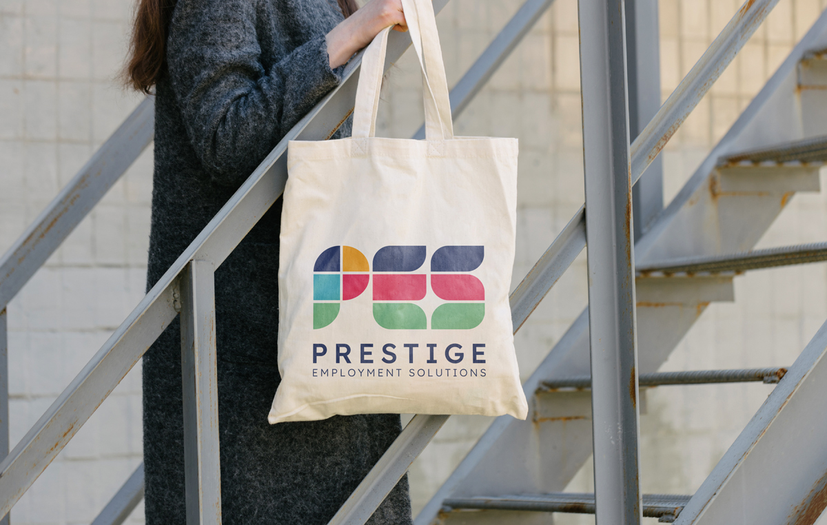 A person holding a tote bag with the colorful "PES Prestige Employment Solutions" logo stands on a metal staircase.